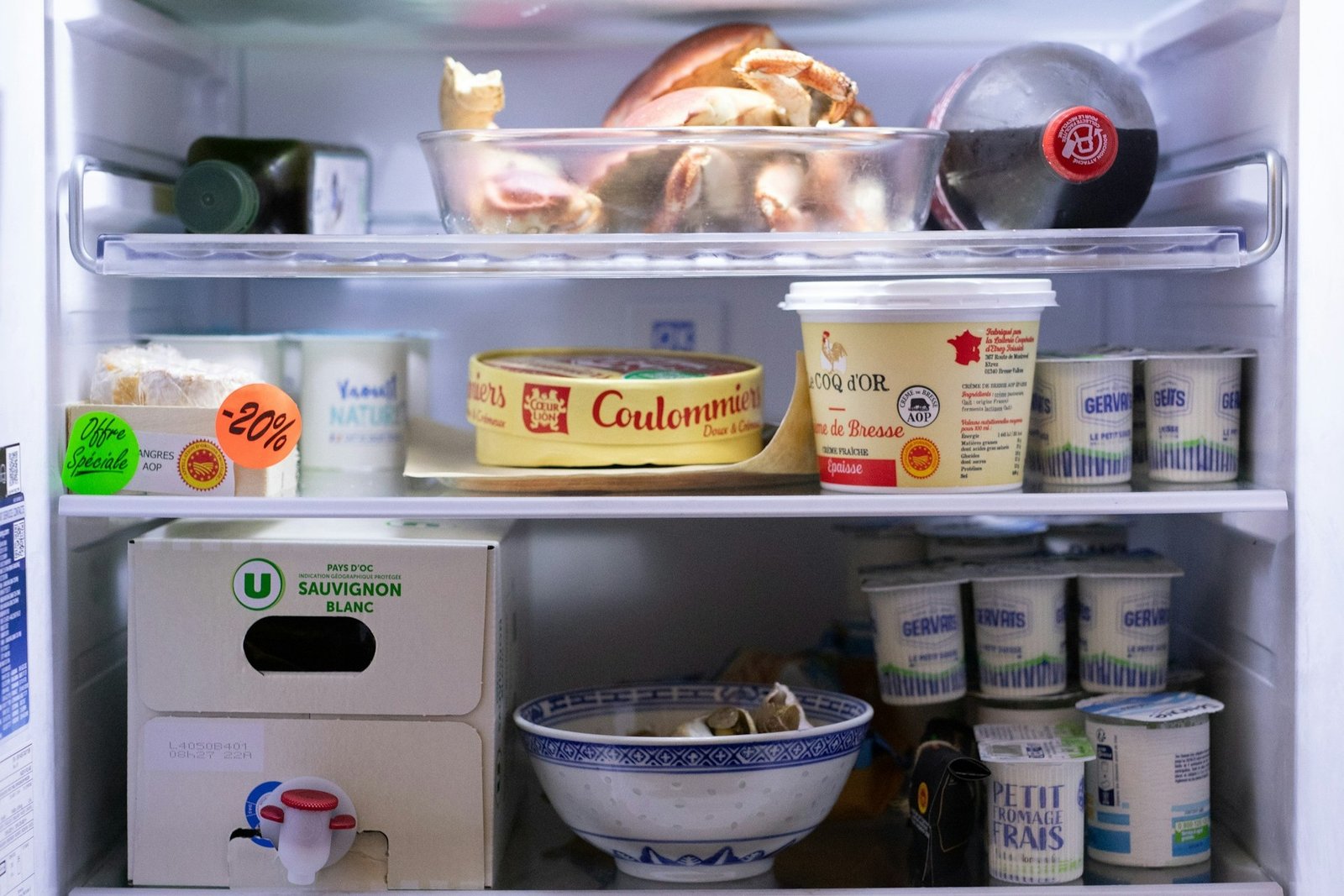 Offener Kühlschrank mit verschiedenen Lebensmitteln auf mehreren Fächern