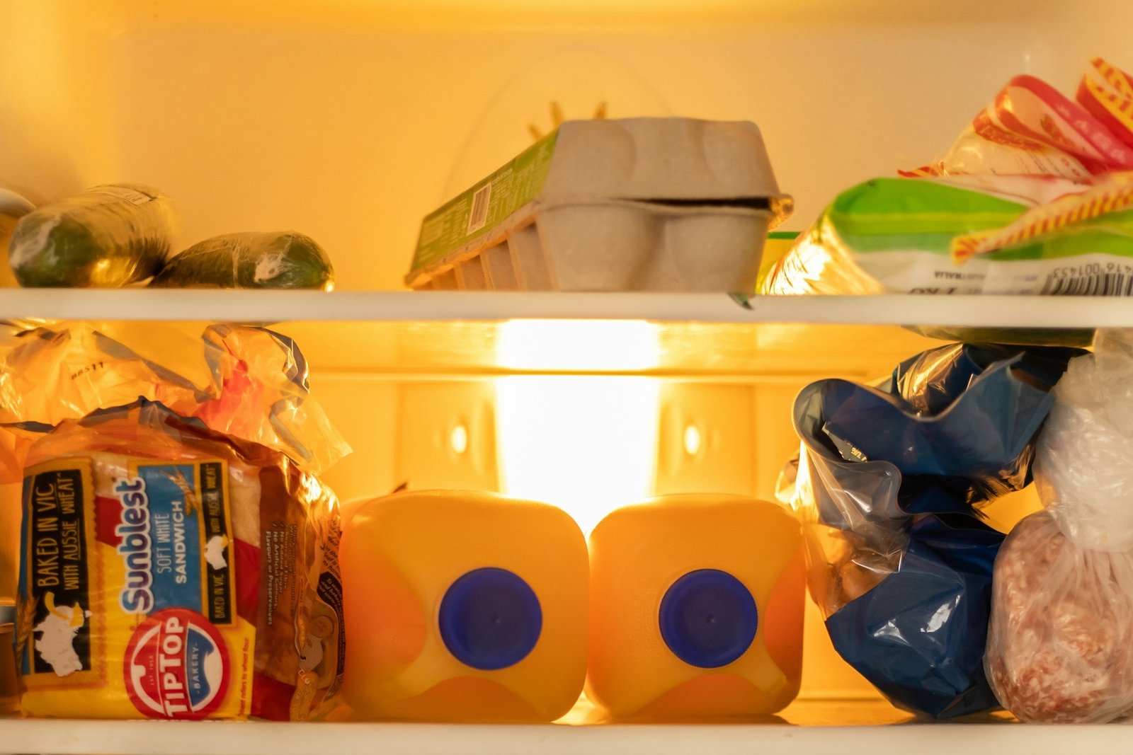 Offener Kühlschrank in einer Küche mit sichtbaren Lebensmitteln auf mehreren Ebenen