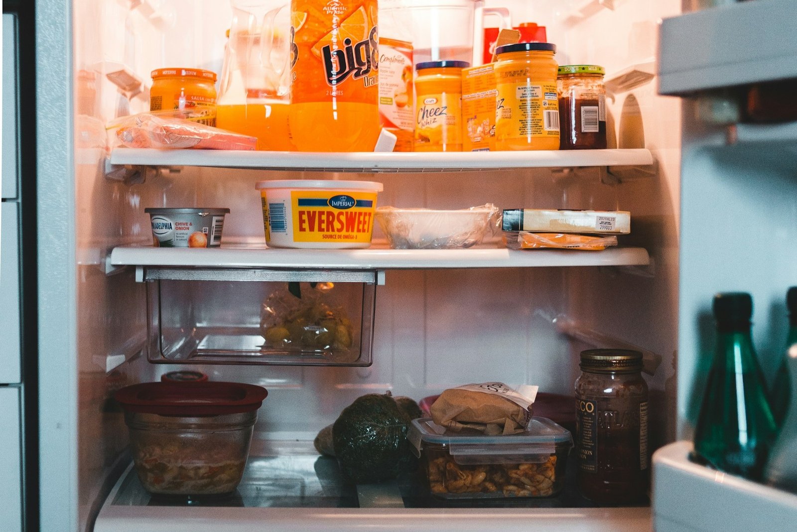 Geöffneter Kühlschrank in einer Küche mit sichtbaren Lebensmitteln auf den Fächern